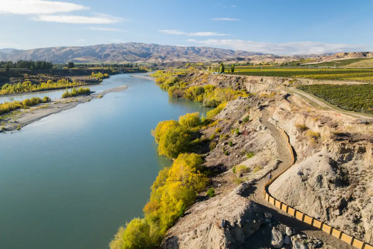 Aerial view of the Kawarau Gorge Trail hugging the cliff above the river with vineyards beyond